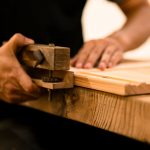 A skilled woodworker shaping wood with a hand tool in a workshop, showcasing craftsmanship and precision.