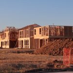 Wooden frames of new homes under construction in Elk Grove, California during sunset.