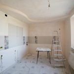 Spacious kitchen under renovation with ladder and tools, showcasing a fresh new design.