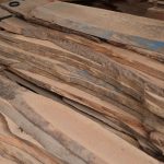 Stack of wooden planks in a workshop setting, ideal for woodworking projects.
