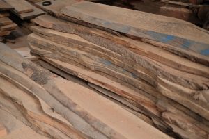 Stack of wooden planks in a workshop setting, ideal for woodworking projects.