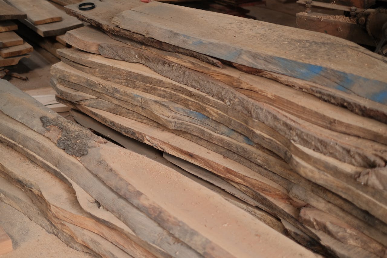 Stack of wooden planks in a workshop setting, ideal for woodworking projects.