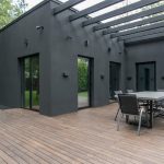 Contemporary black house with spacious wooden terrace and outdoor seating area.